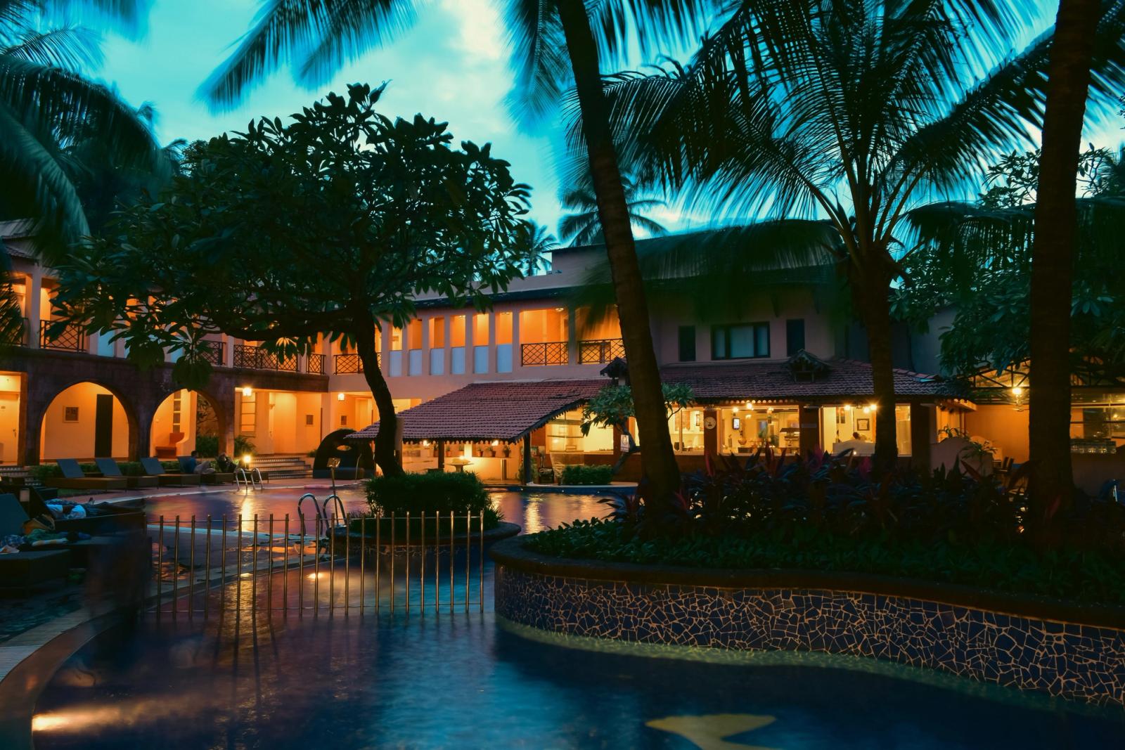 Serene night view of a tropical resort with palm trees and a lit swimming pool