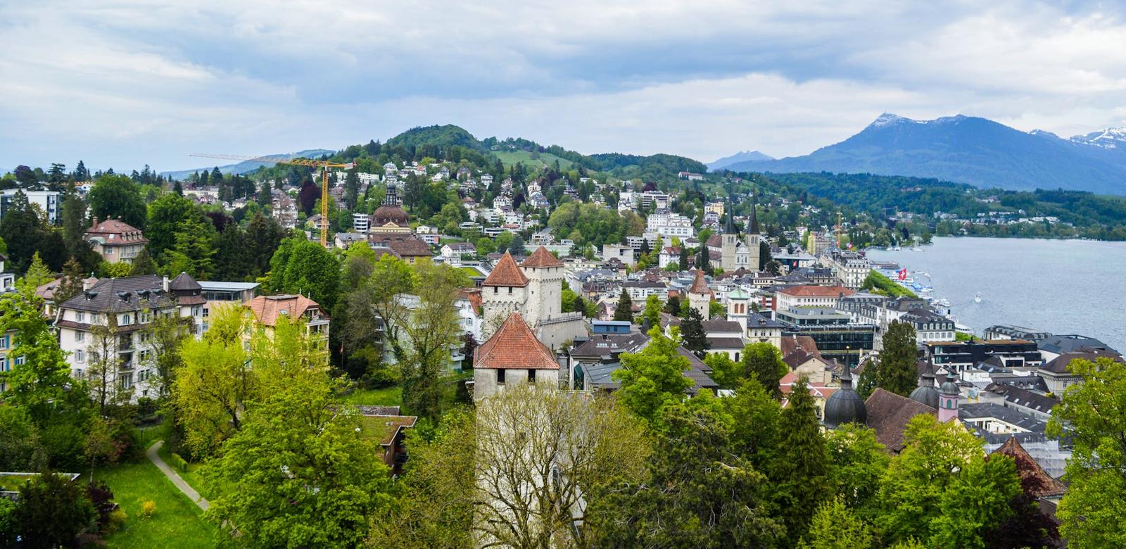 From above of green medieval town with green trees on coast of blue sea