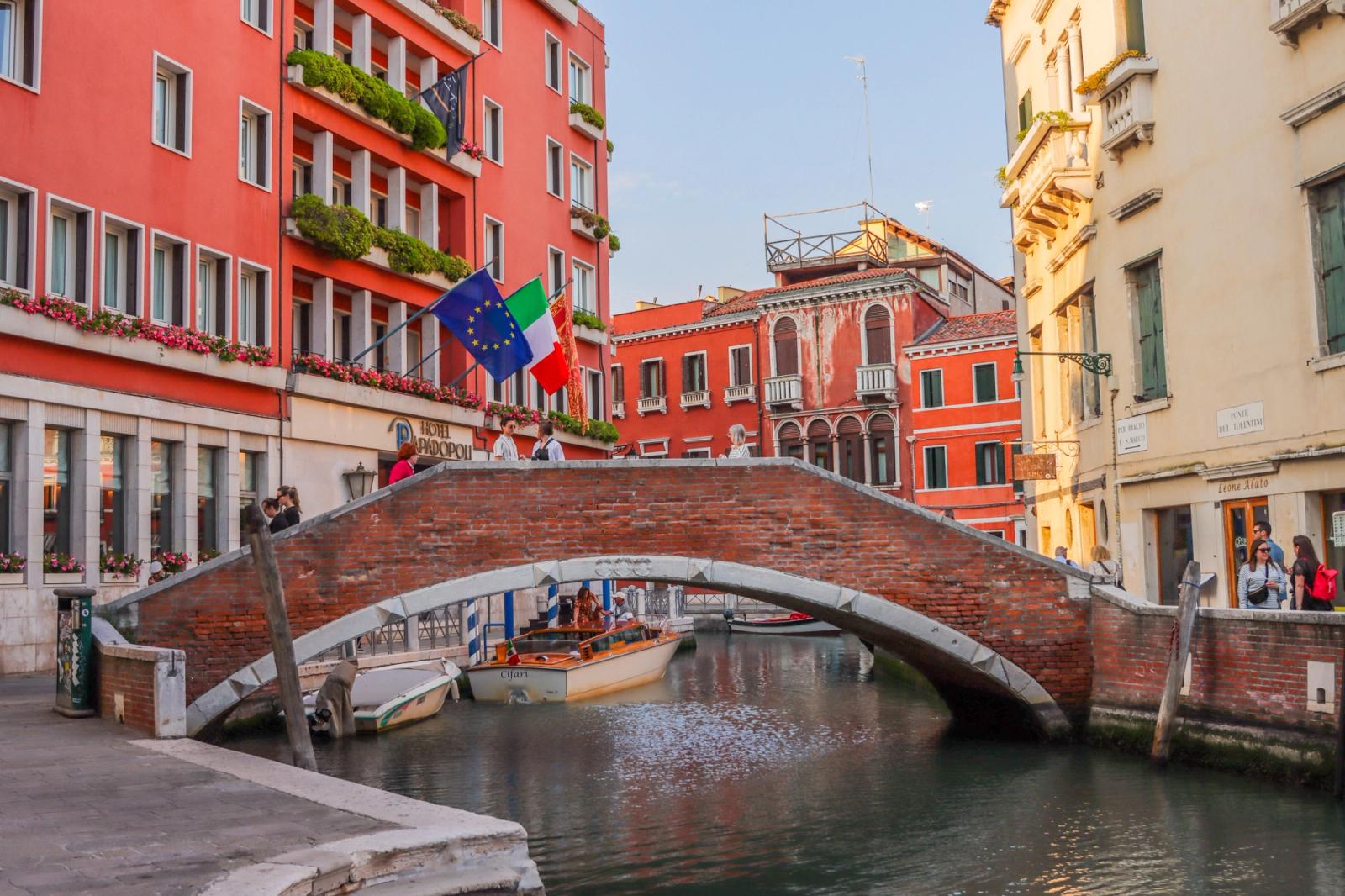 Charming view of a Venetian canal with traditional architecture, bridge, and flags in Venice, Italy