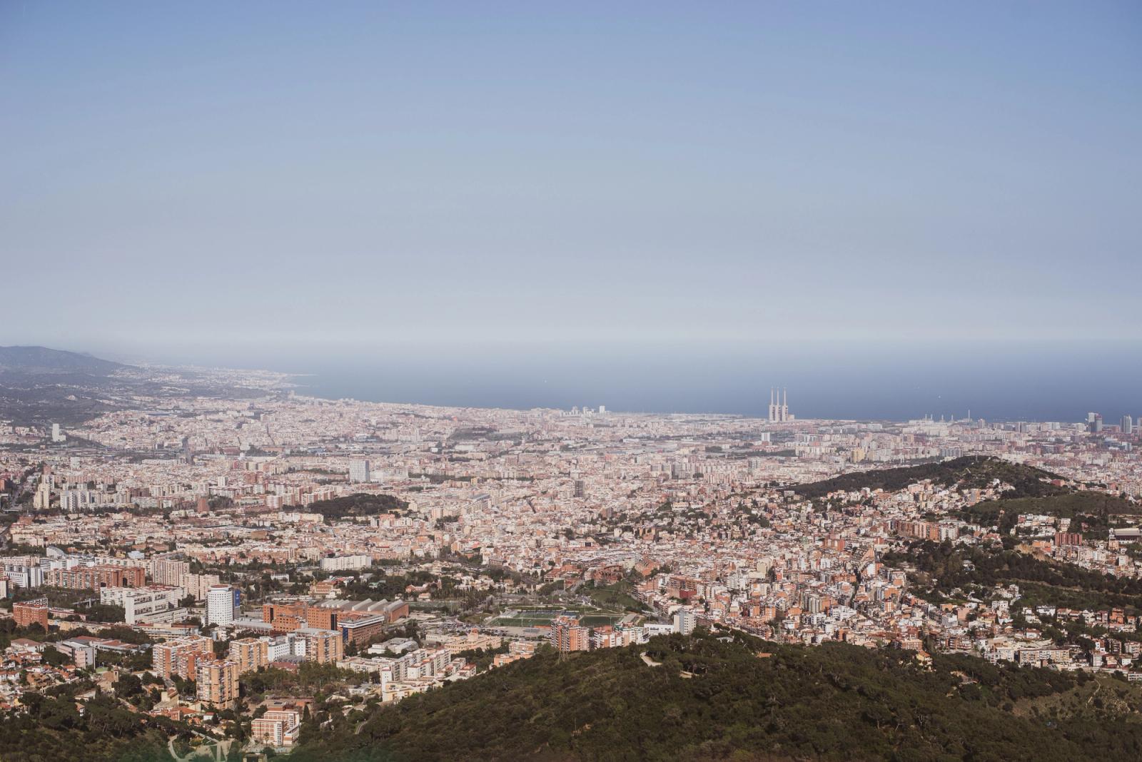 Stunning aerial view of Barcelona city with its coastline and iconic landmarks under a clear sky