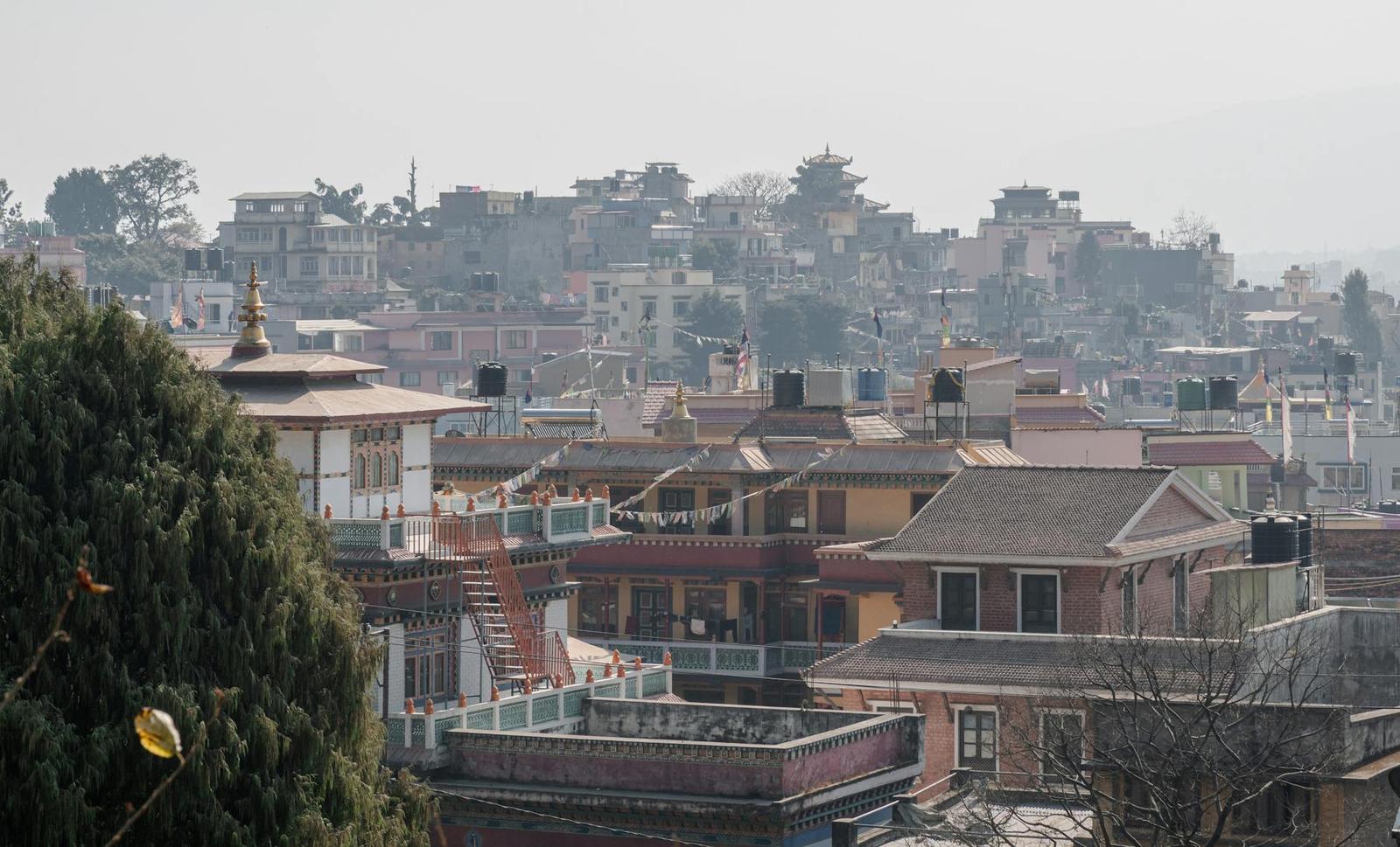 Hazy hillside town of terraced rooftops with a temple spire in the foreground