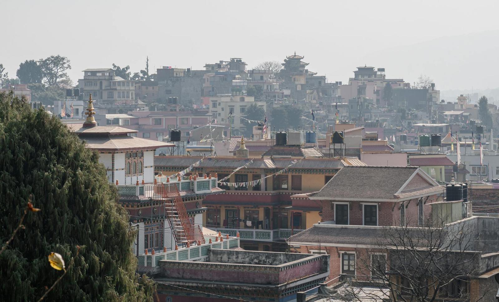 Hazy hillside town of terraced rooftops with a temple spire in the foreground