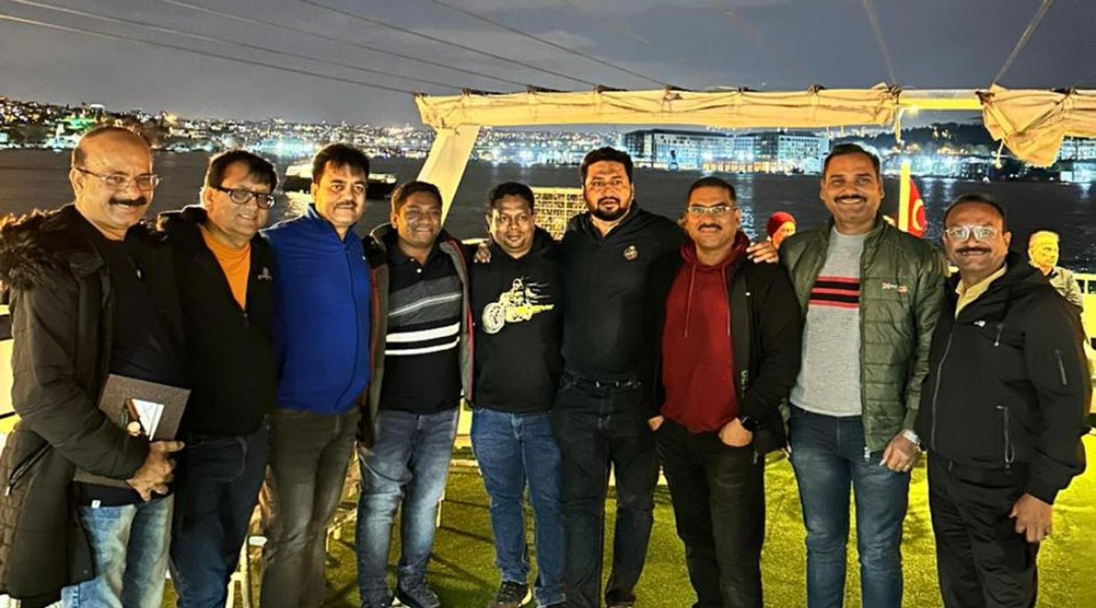 A group of people posing together at night on a deck 
