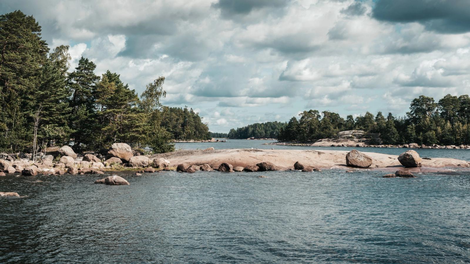 Explore the serene Finnish archipelago featuring lush forests and rocky shores under a cloudy sky
