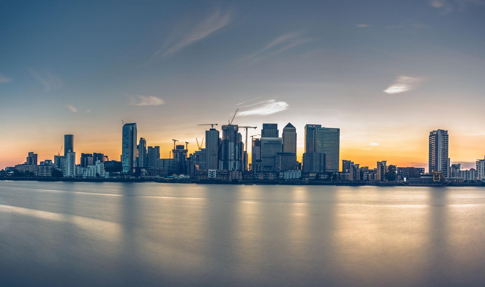 A waterfront city skyline reflected on calm water at dusk