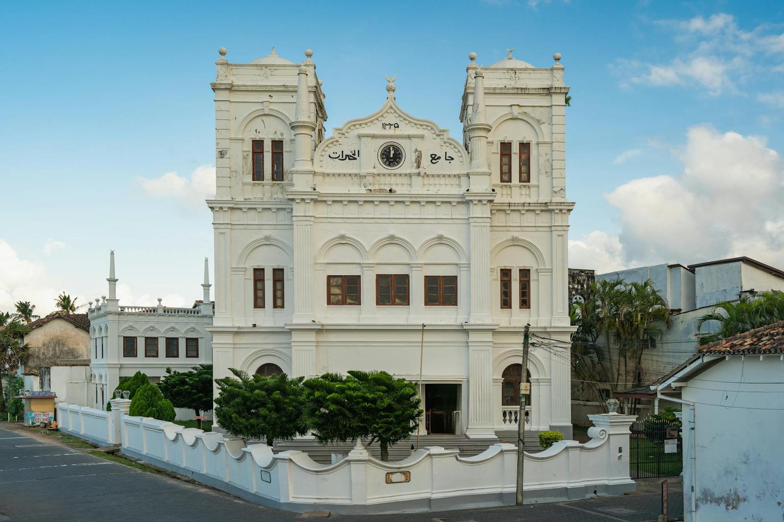 Twin-towered white mosque with arched windows on a street corner