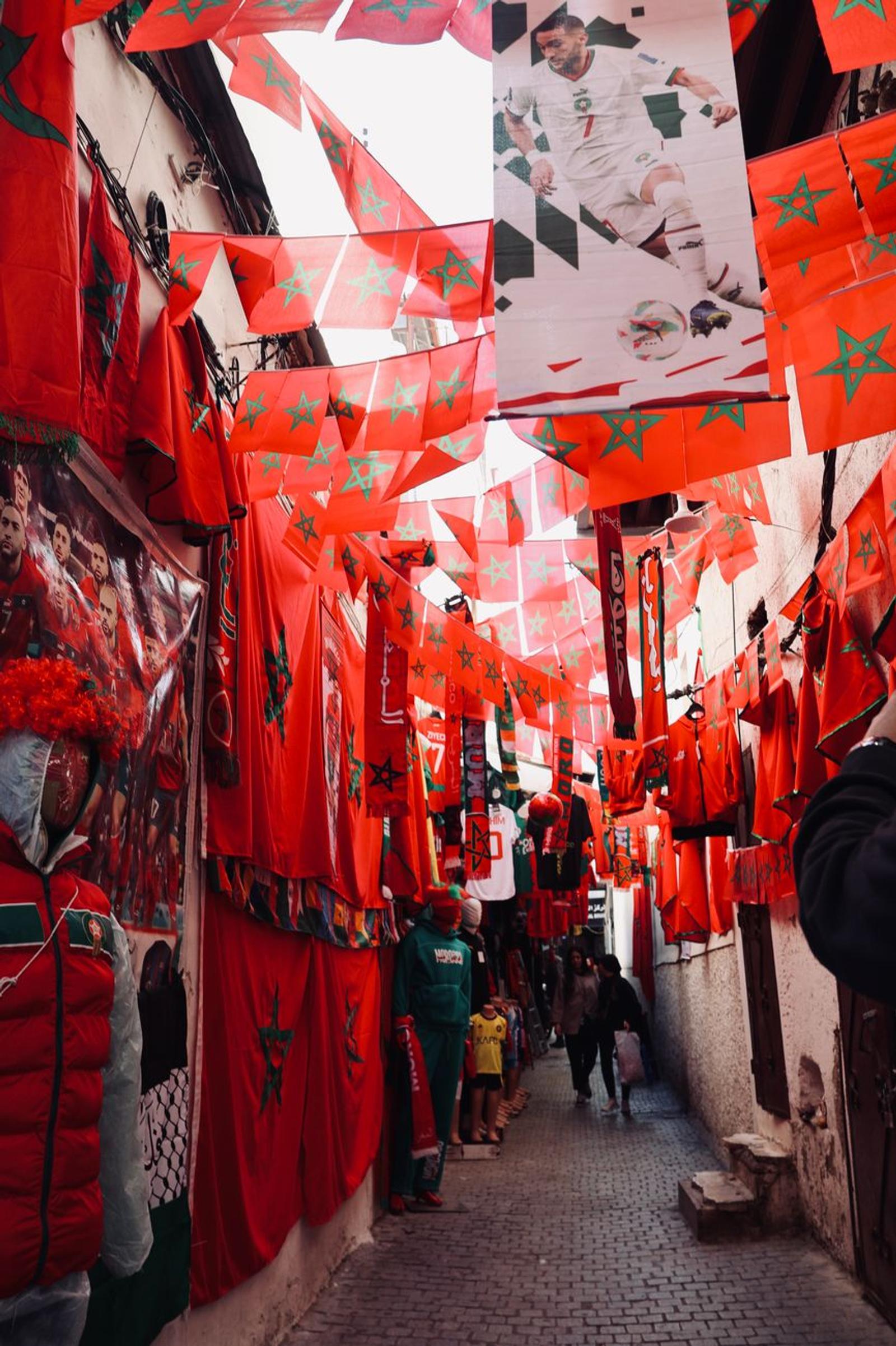 Narrow alley strung with red national flags and football banners overhead