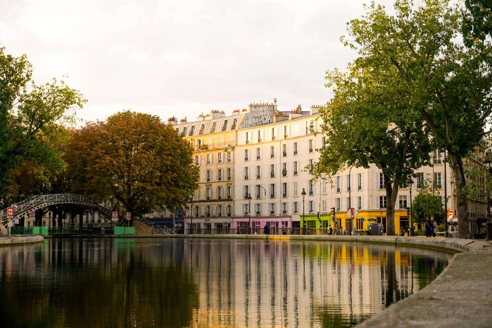 Scenic view of Canal Saint-Martin in Paris with footbridge and colorful buildings reflecting in the water