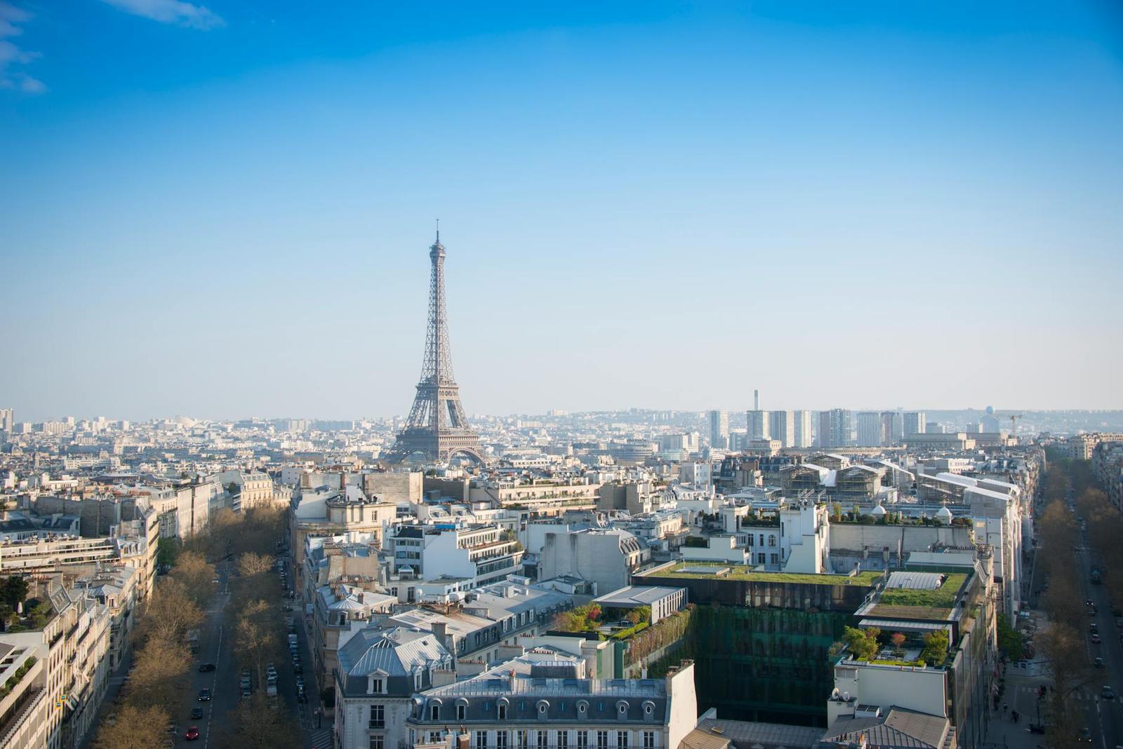 A stunning aerial view of Paris with the iconic Eiffel Tower and cityscape under a clear blue sky