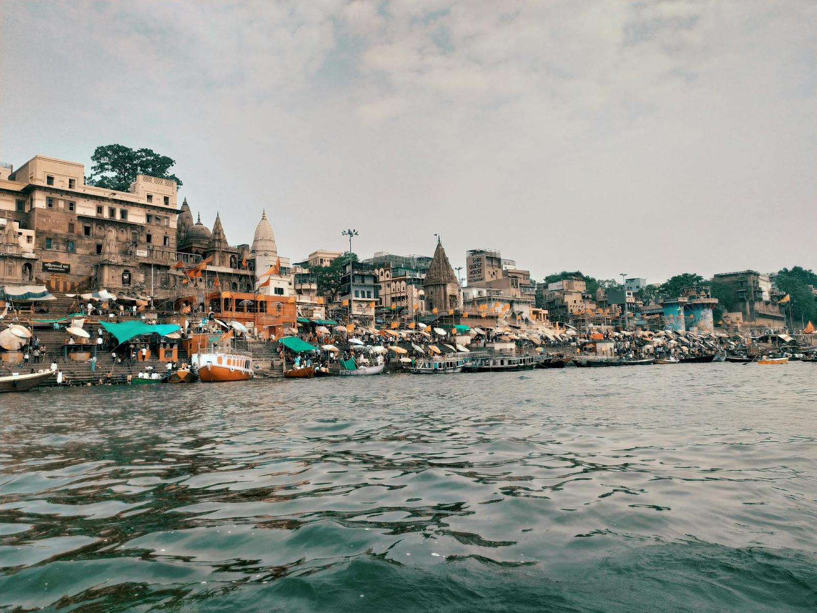 A riverside old town of stacked buildings and temple spires seen from the water