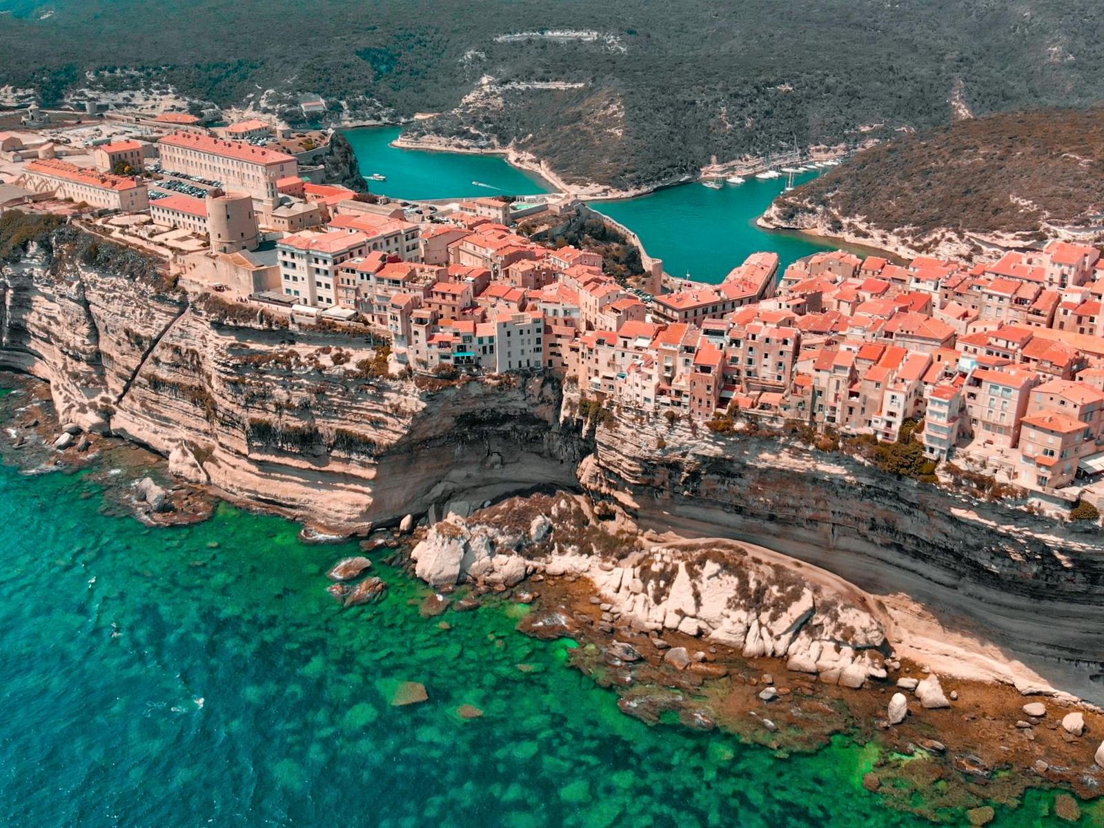 Aerial view of a clifftop coastal town beside turquoise water