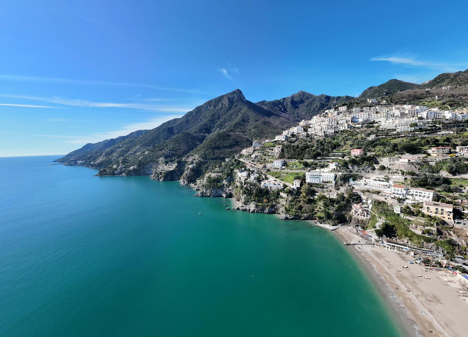 Aerial view of a hillside coastal town above a turquoise bay