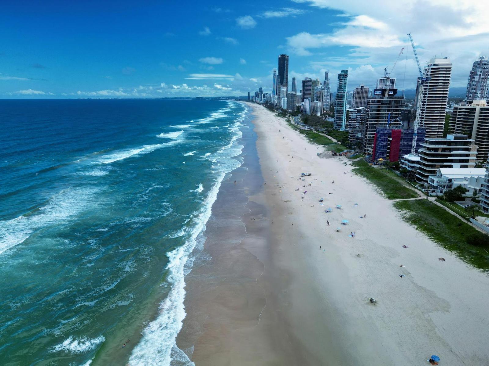 Aerial view along a beach lined with high-rise towers and turquoise surf