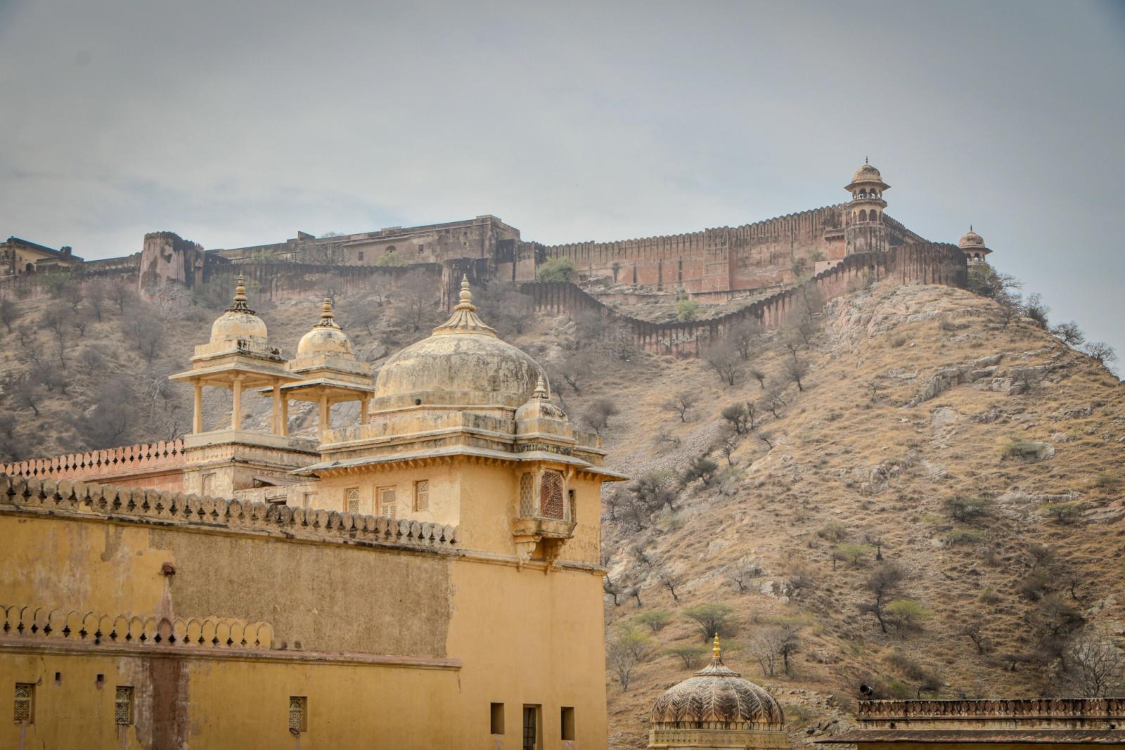 A hillside fort wall stretching above a domed sandstone palace