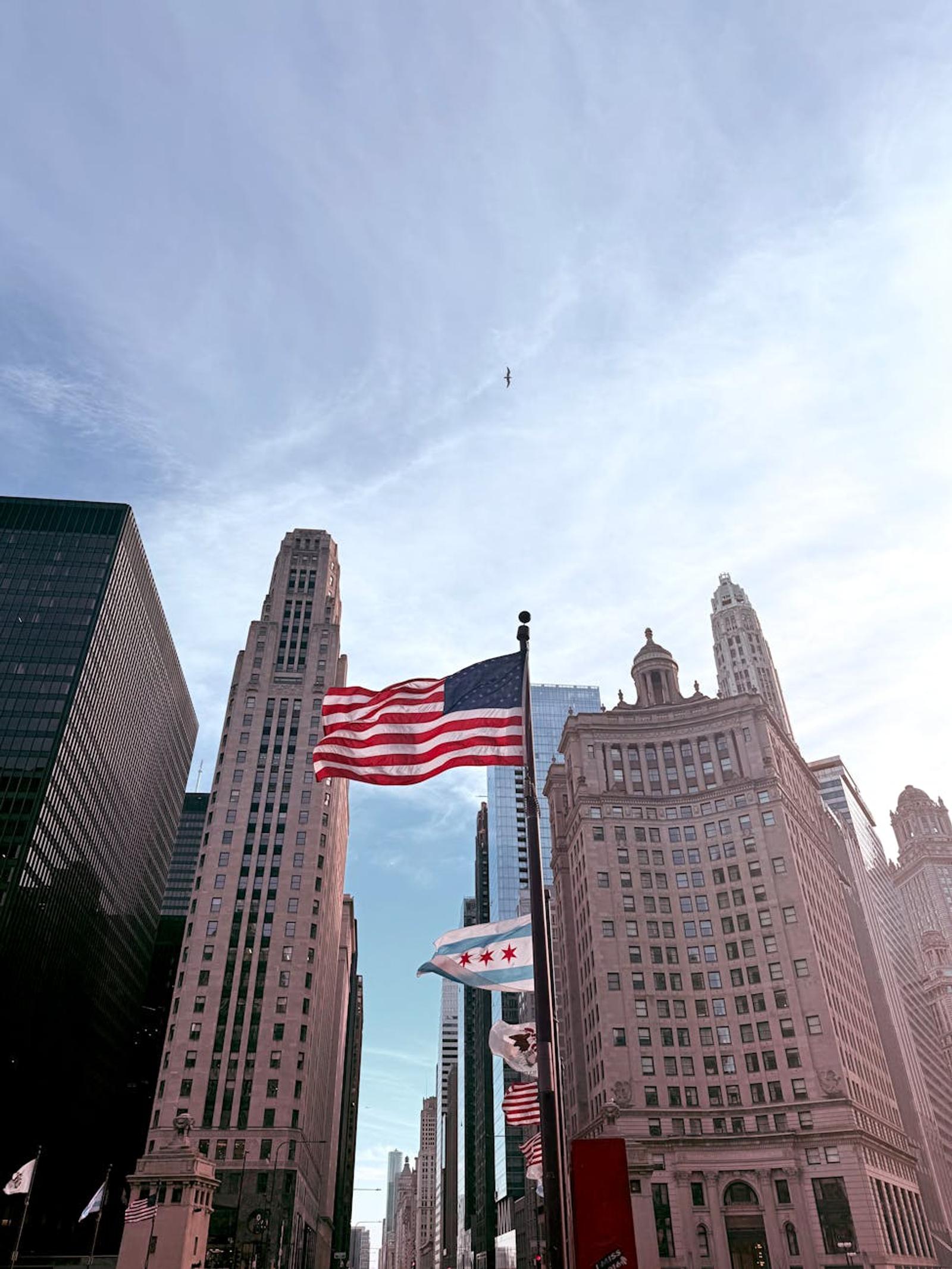 American and Chicago flags waving amidst historic skyscrapers in downtown Chicago