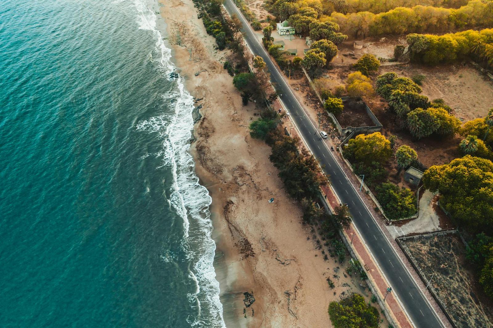 Aerial view of a coastal road running beside a sandy shoreline