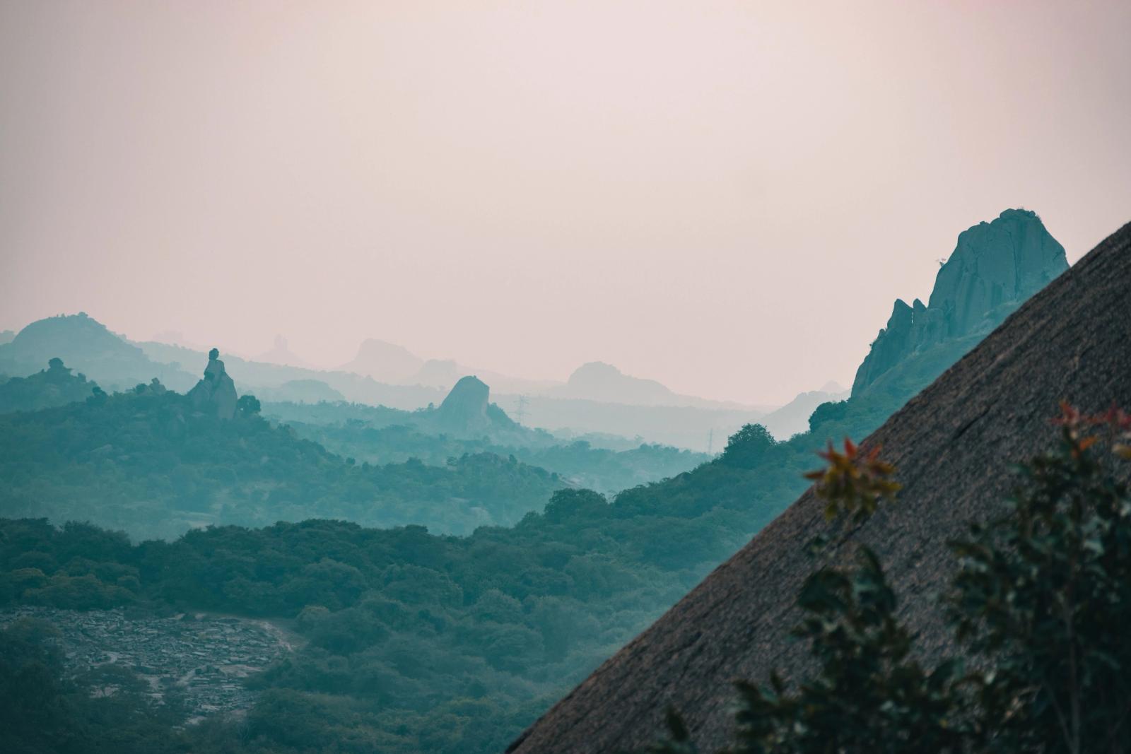 A tranquil view of misty hills and lush forests in Mysuru, India, captured at dawn