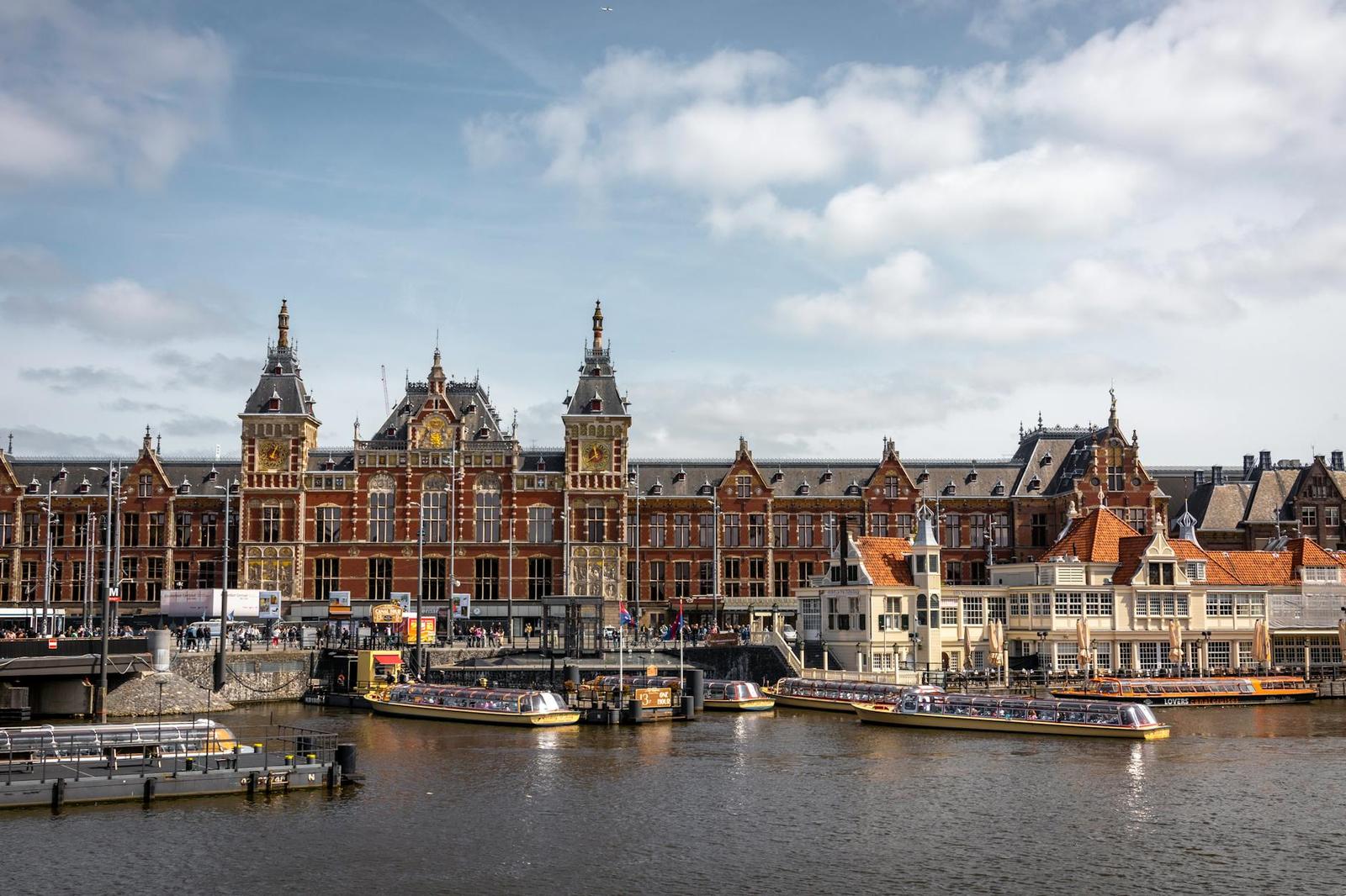 Ornate brick station tower rising above canal boats moored at a waterfront