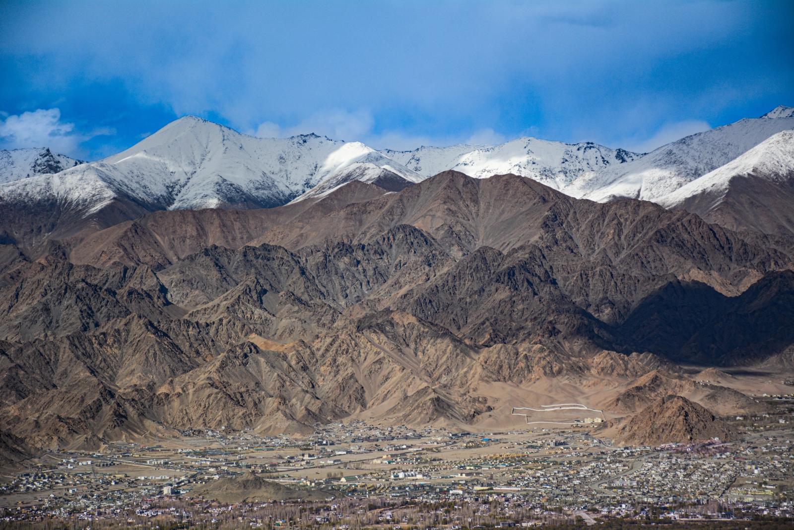 Stunning view of Leh city nestled below the snow-capped Himalayas under a clear blue sky