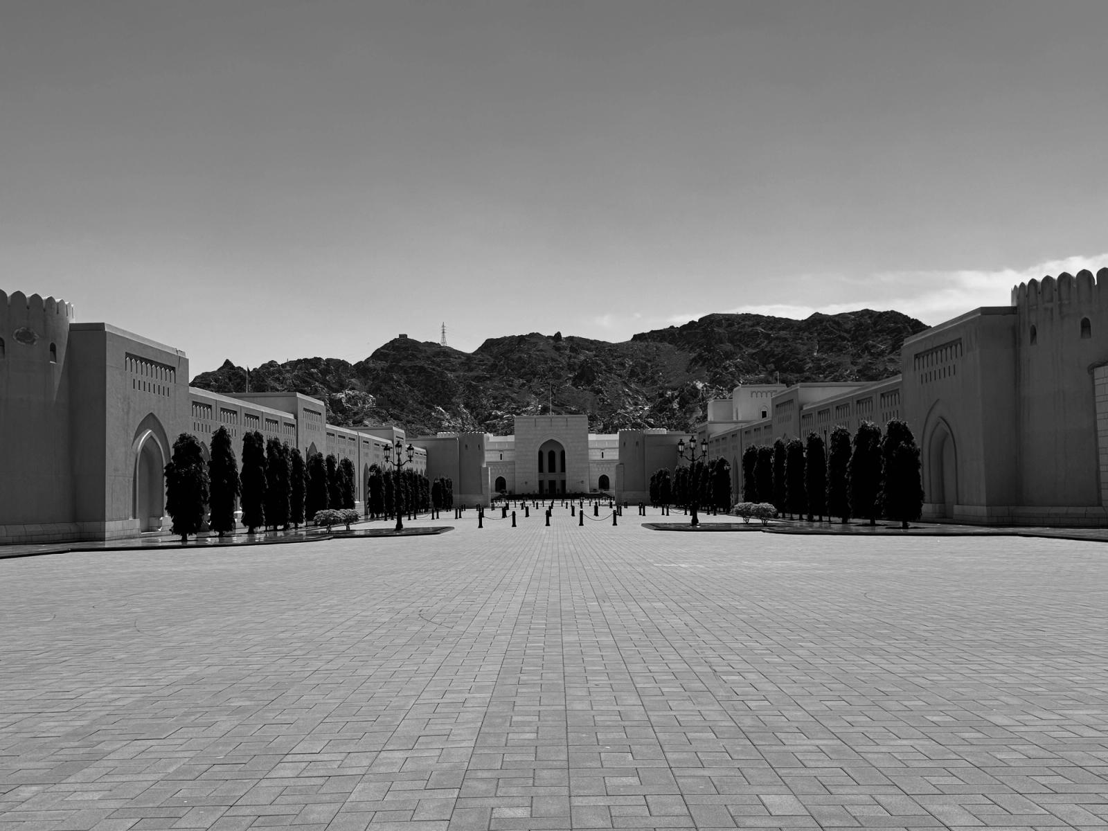Black and white view of a striking architectural complex framed by mountains in Muscat, Oman