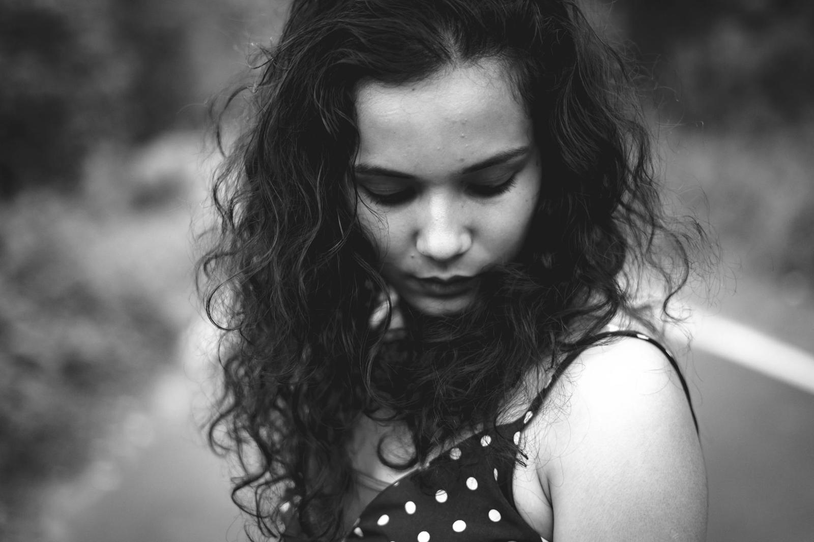 Black and white close-up of a young woman with curly hair looking down