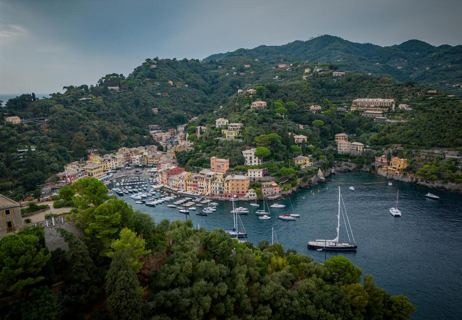 Aerial view of a colourful harbour village nestled in a wooded bay