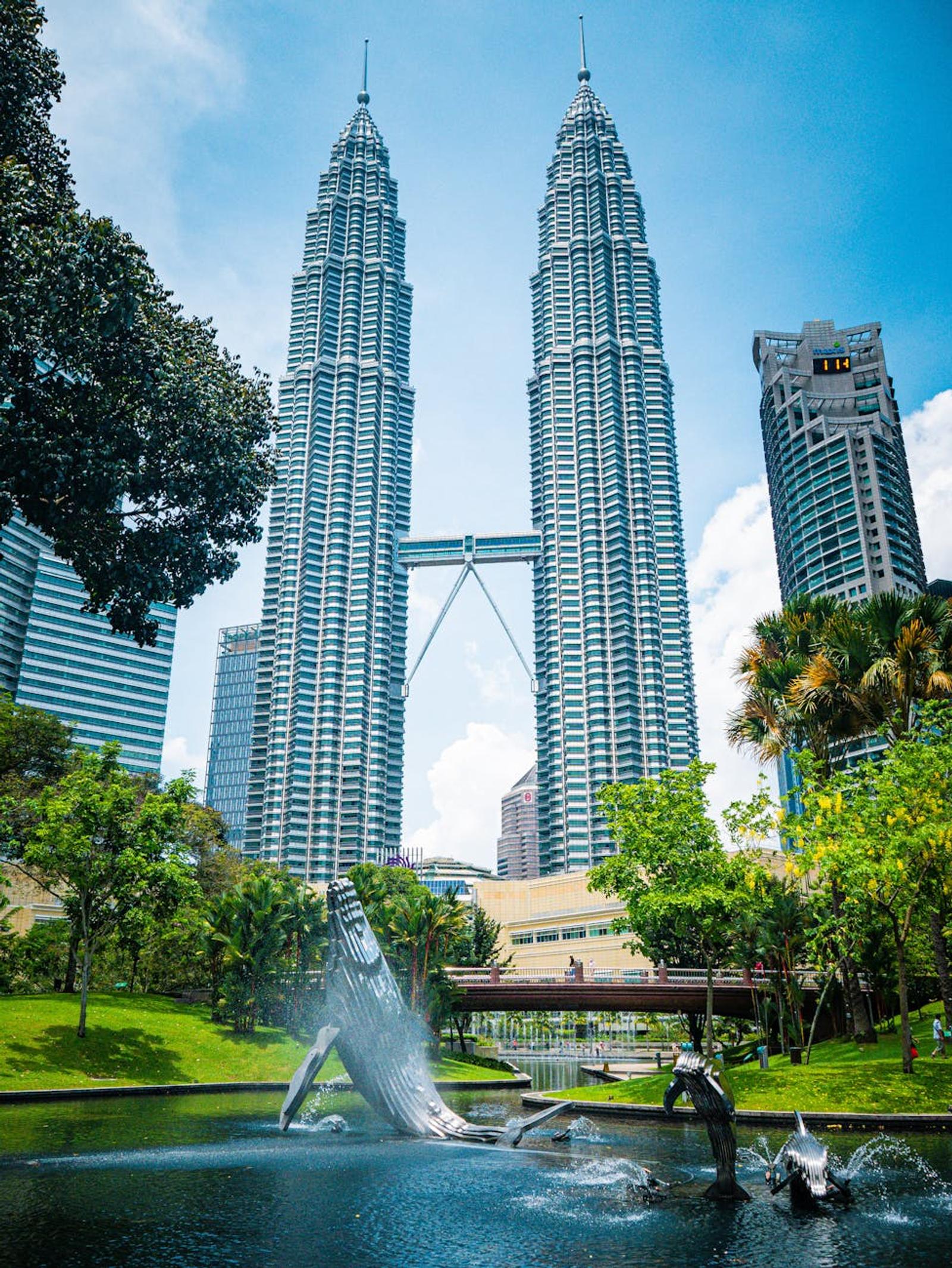 View of Petronas Twin Towers and surrounding park in Kuala Lumpur under a blue sky