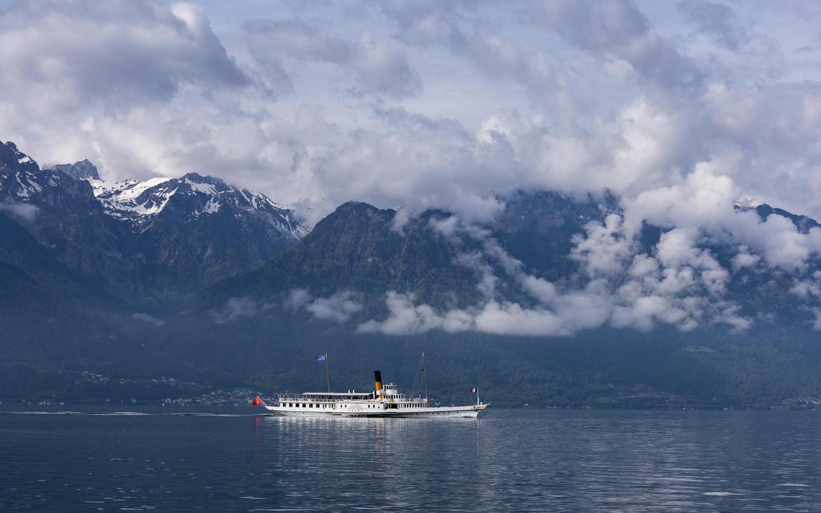 Vintage steamboat sailing beneath cloud-shrouded mountains