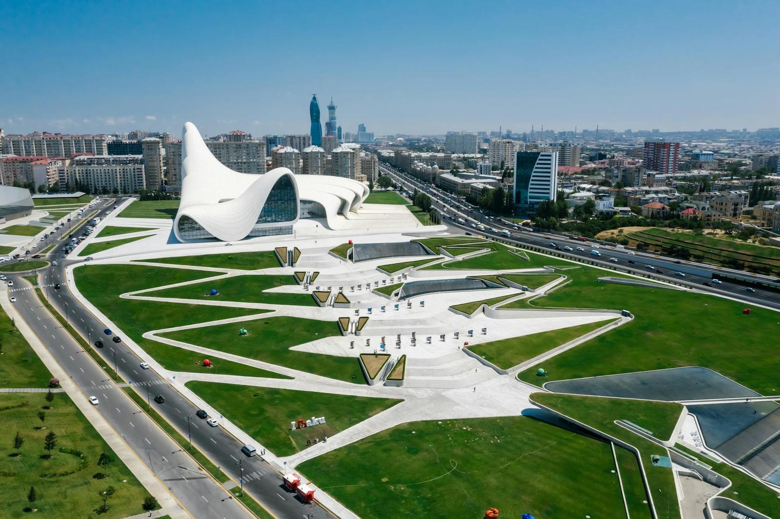 Aerial view of an undulating white building set in landscaped grounds