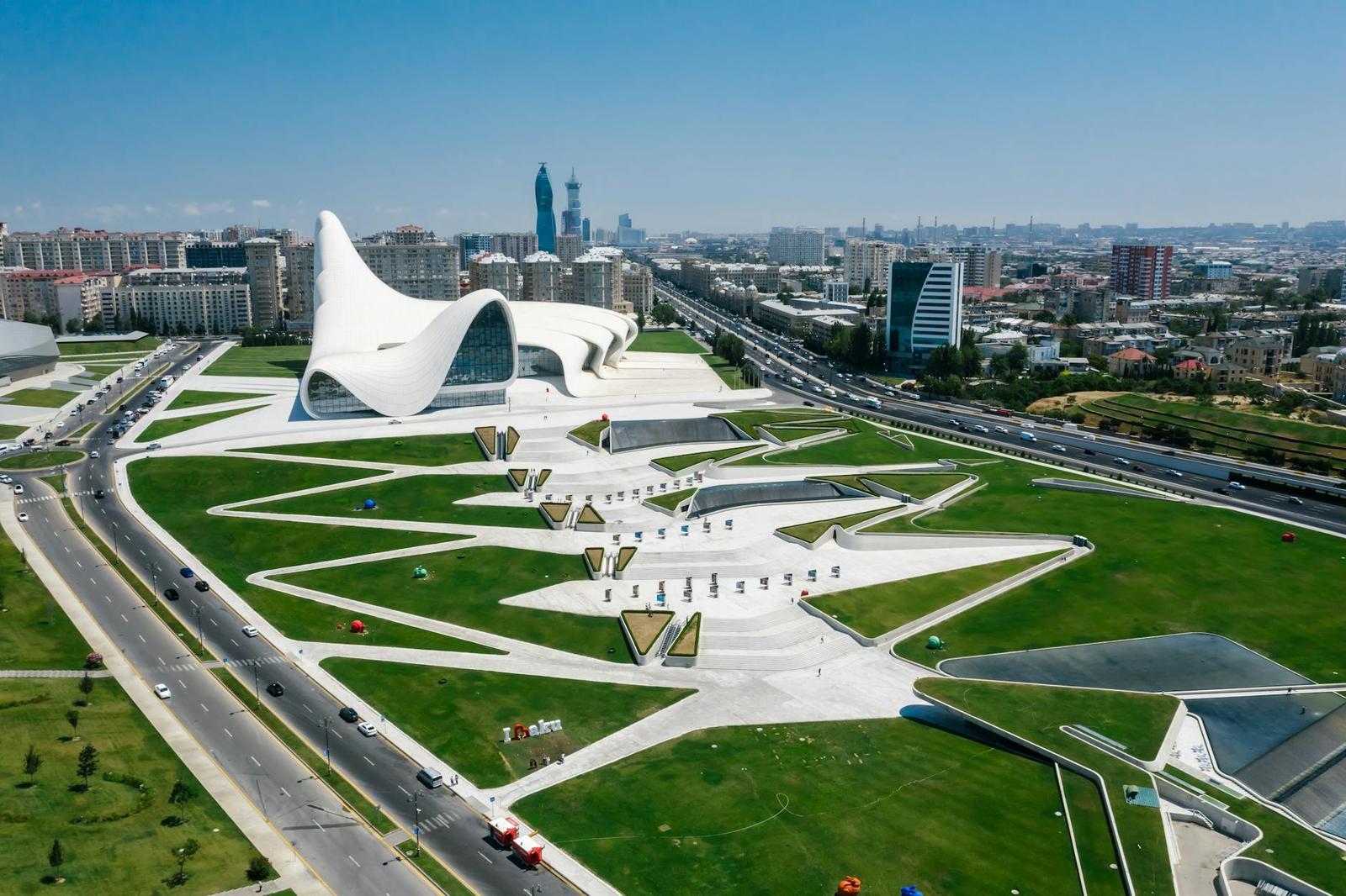 Aerial view of an undulating white building set in landscaped grounds