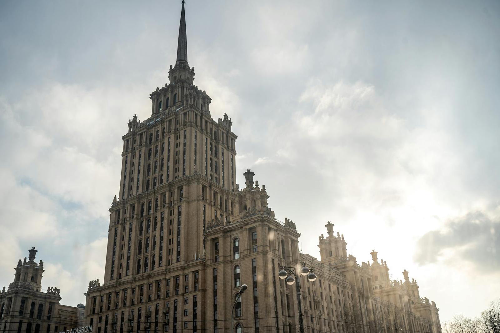 A tall tiered stone tower topped with a slender spire against a bright sky