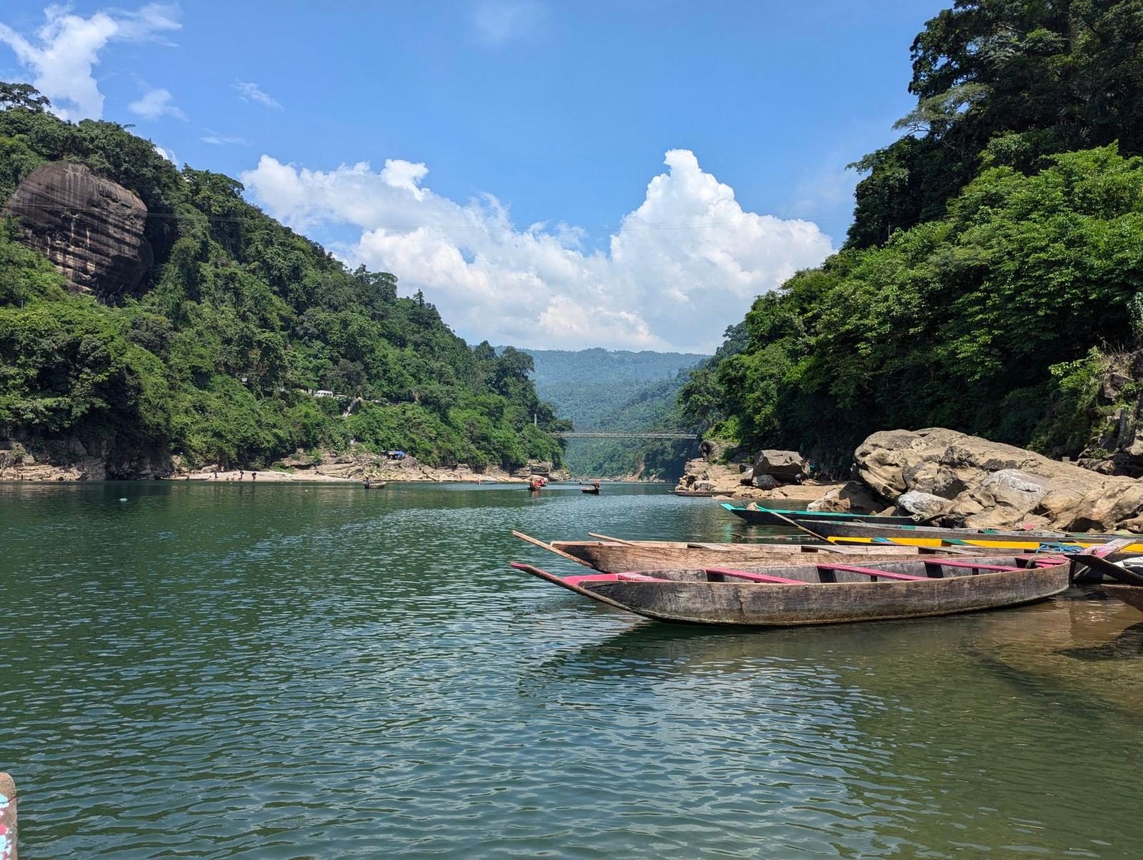 Wooden boats moored on a river winding through forested cliffs