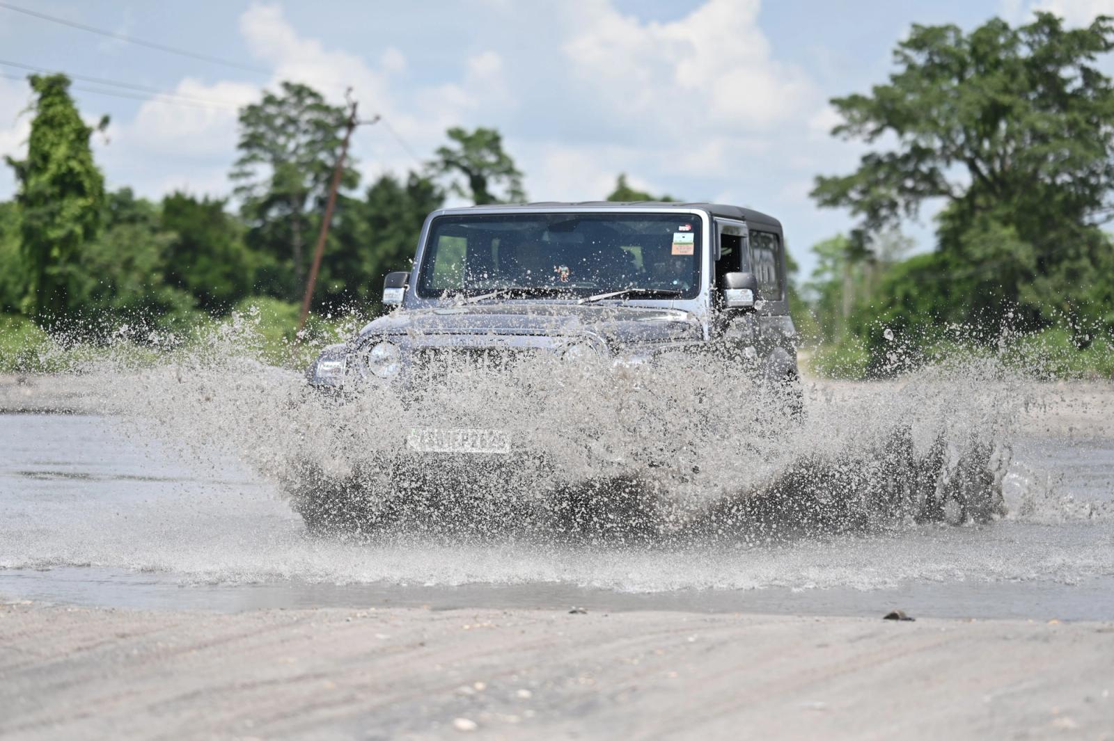 A silver 4x4 jeep splashes through water in an adventure drive near Guwahati, India