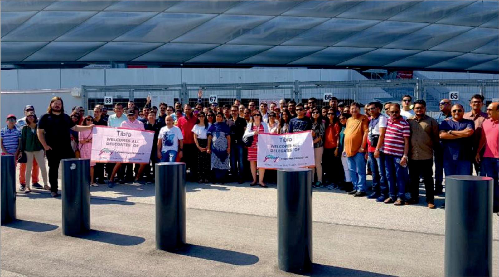 A group of people posing with a welcome banner outdoors.