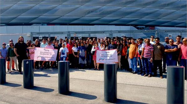 A group of people posing with a welcome banner outdoors.