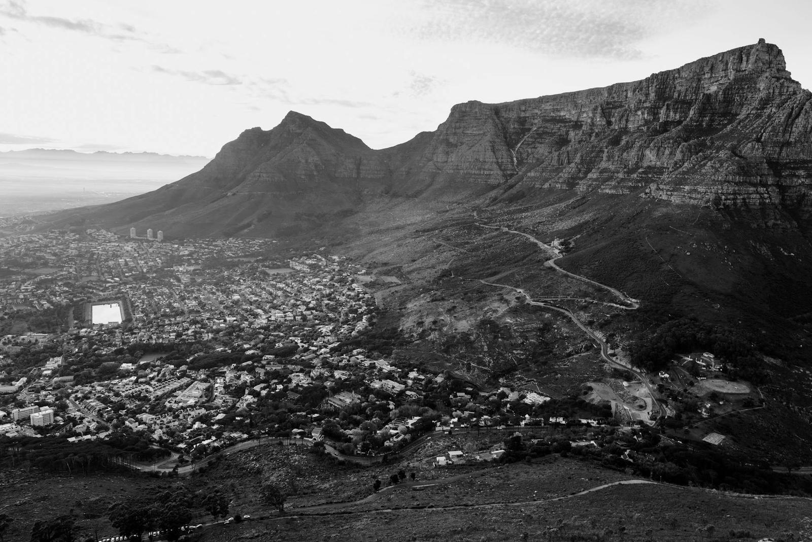 Black and white aerial view of a city nestled beneath rugged mountains