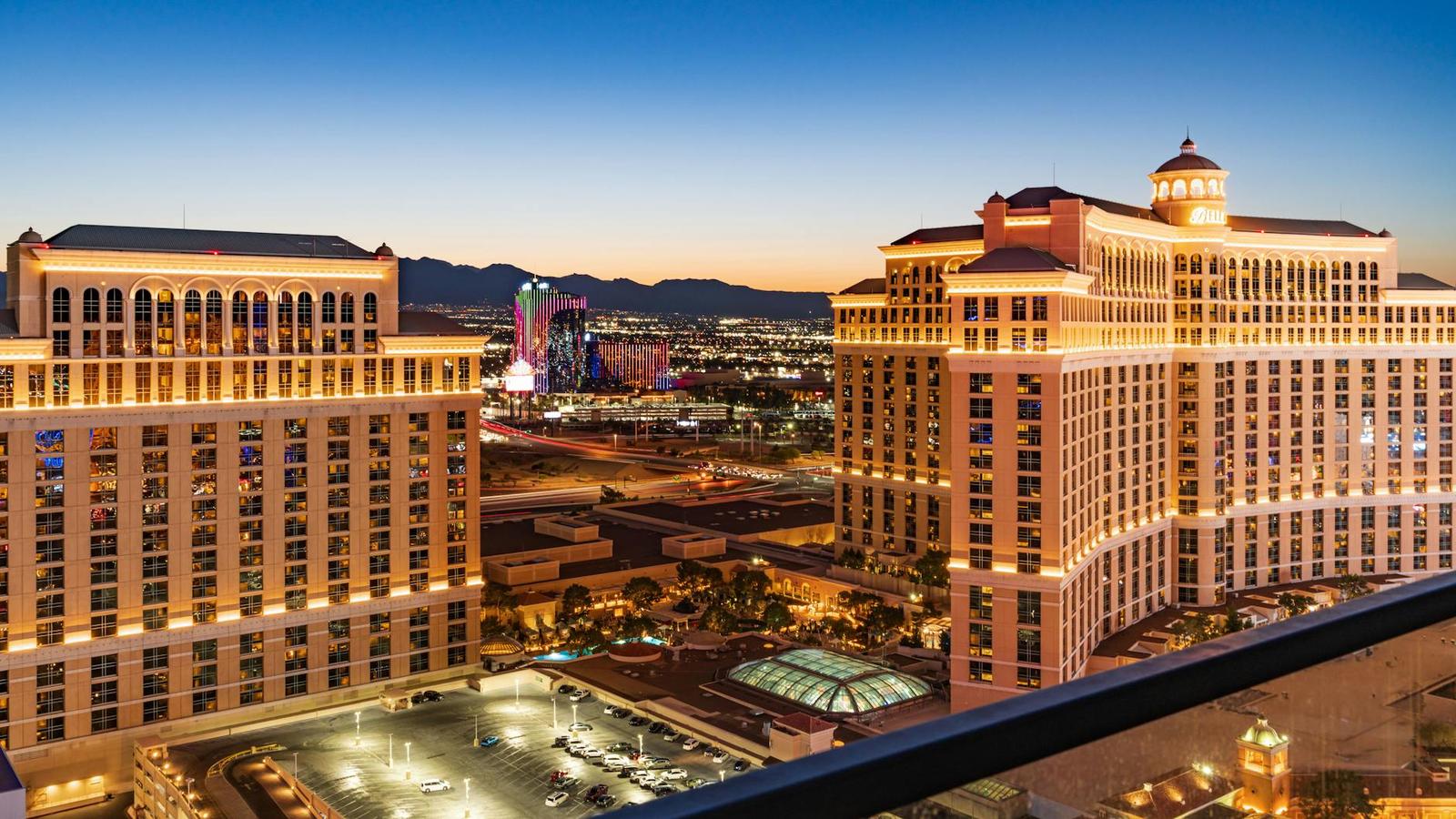 An elevated view of two grand hotel resorts lit up at dusk with mountains behind