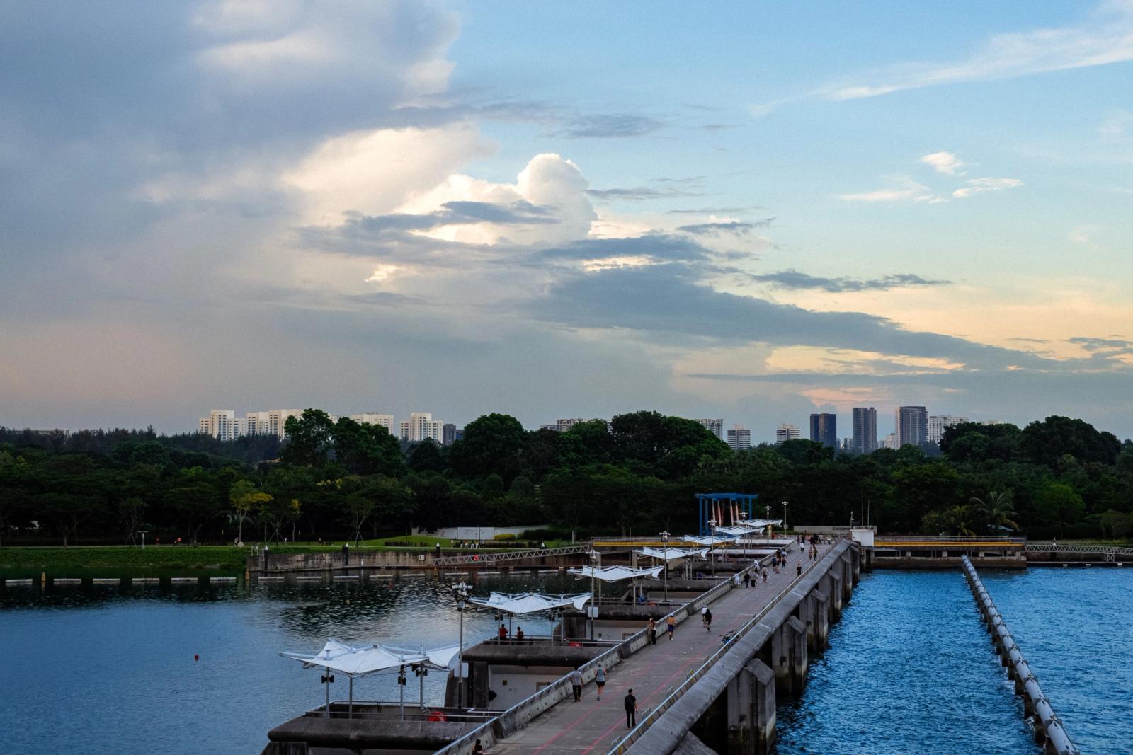 A scenic view of a jetty leading towards the skyline, set against a dramatic sky in Singapore