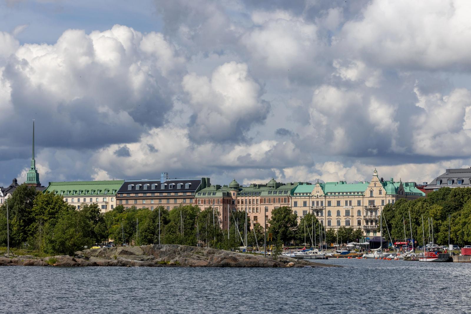 Urban landscape of Helsinki with historic buildings along the waterfront under a cloudy sky