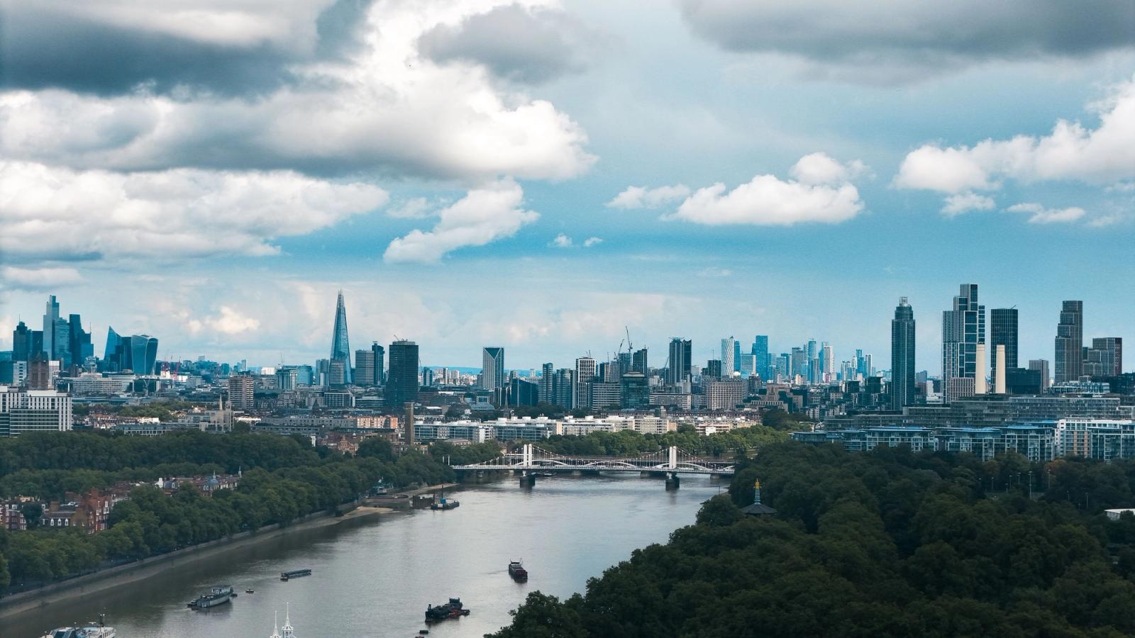 A breathtaking view of London's skyline with the River Thames flowing under dramatic clouds
