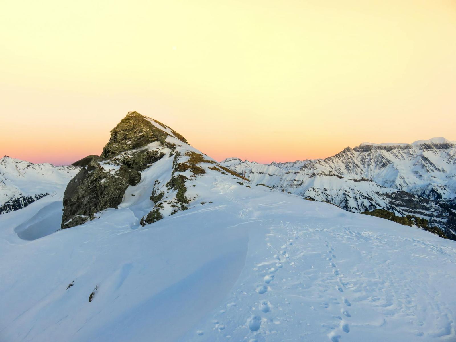 Footprints trailing across a snowy ridge at dawn