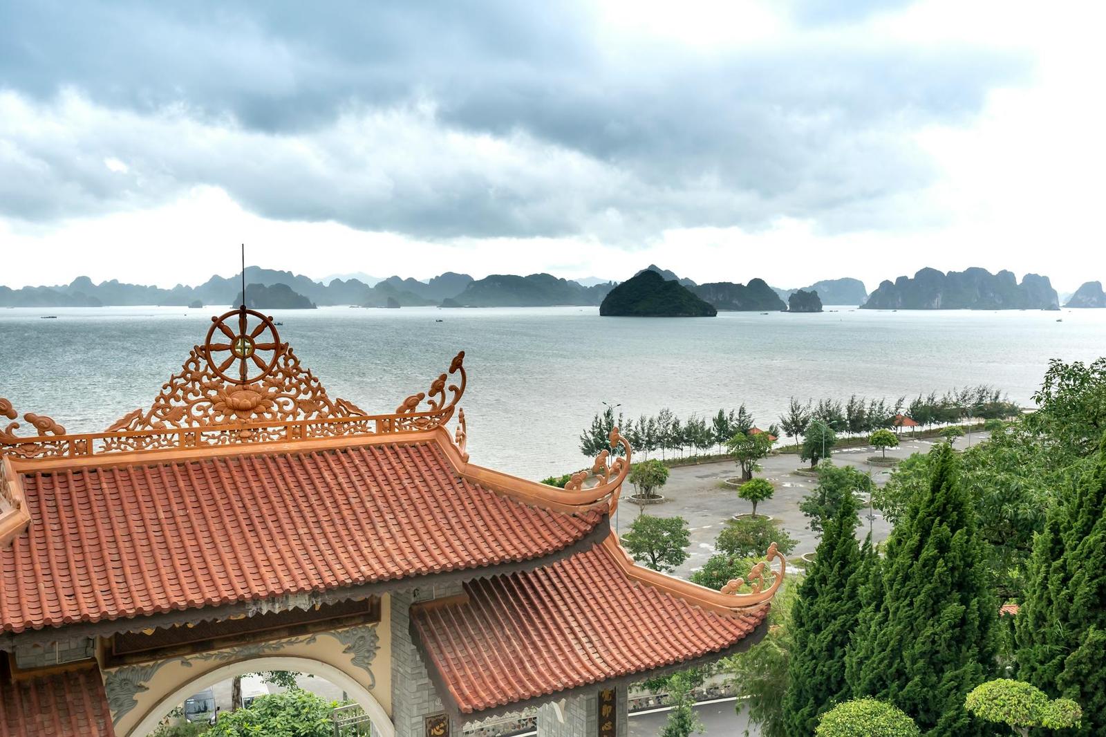 Ornate temple rooftop overlooking a bay scattered with limestone islands