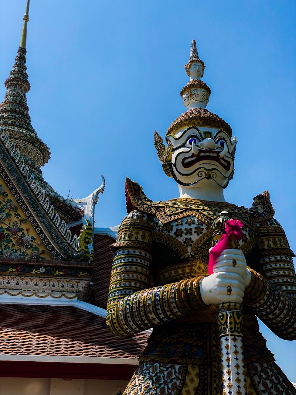 Ornate guardian statue standing before a tiled temple roofline
