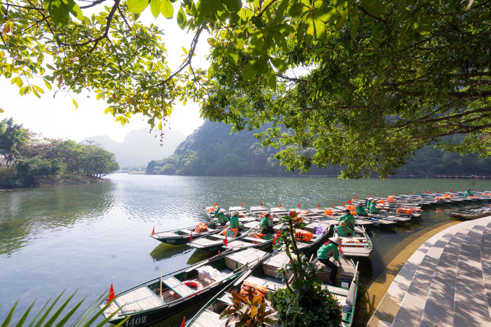 Peaceful scene of docked boats along the riverbank surrounded by lush greenery in Ninh Bình, Vietnam