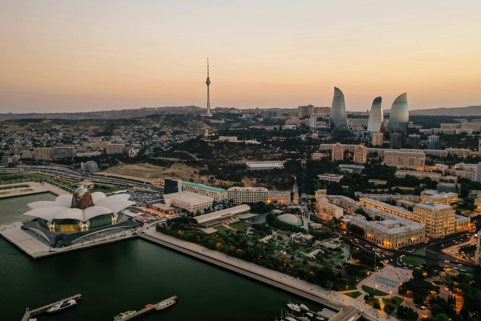 Aerial view of Baku's skyline featuring the Flame Towers and Caspian Sea at dusk