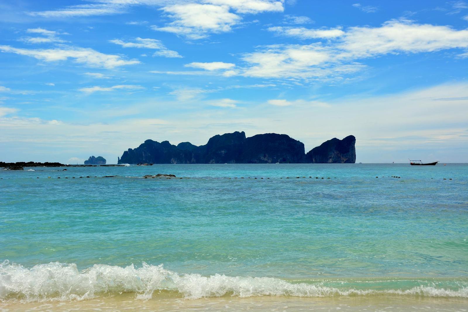 Relaxing beach scene in Ao Nang, Krabi, Thailand with clear blue waters and distant islands