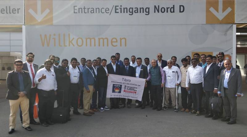 A large group of professionals posing with a 'Tibro' banner