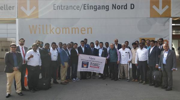 A large group of professionals posing with a 'Tibro' banner