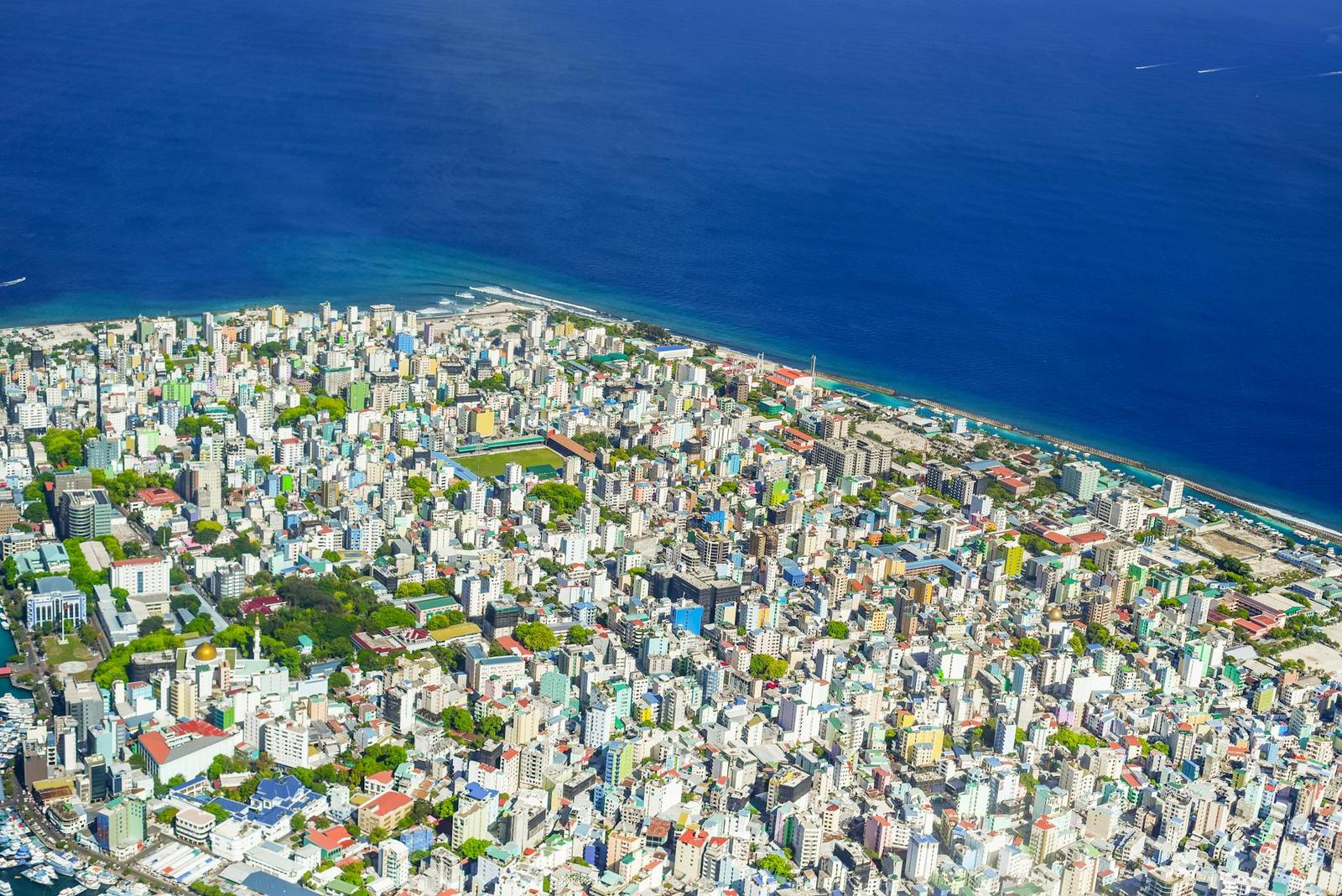 Aerial view of a densely built island city ringed by reef water