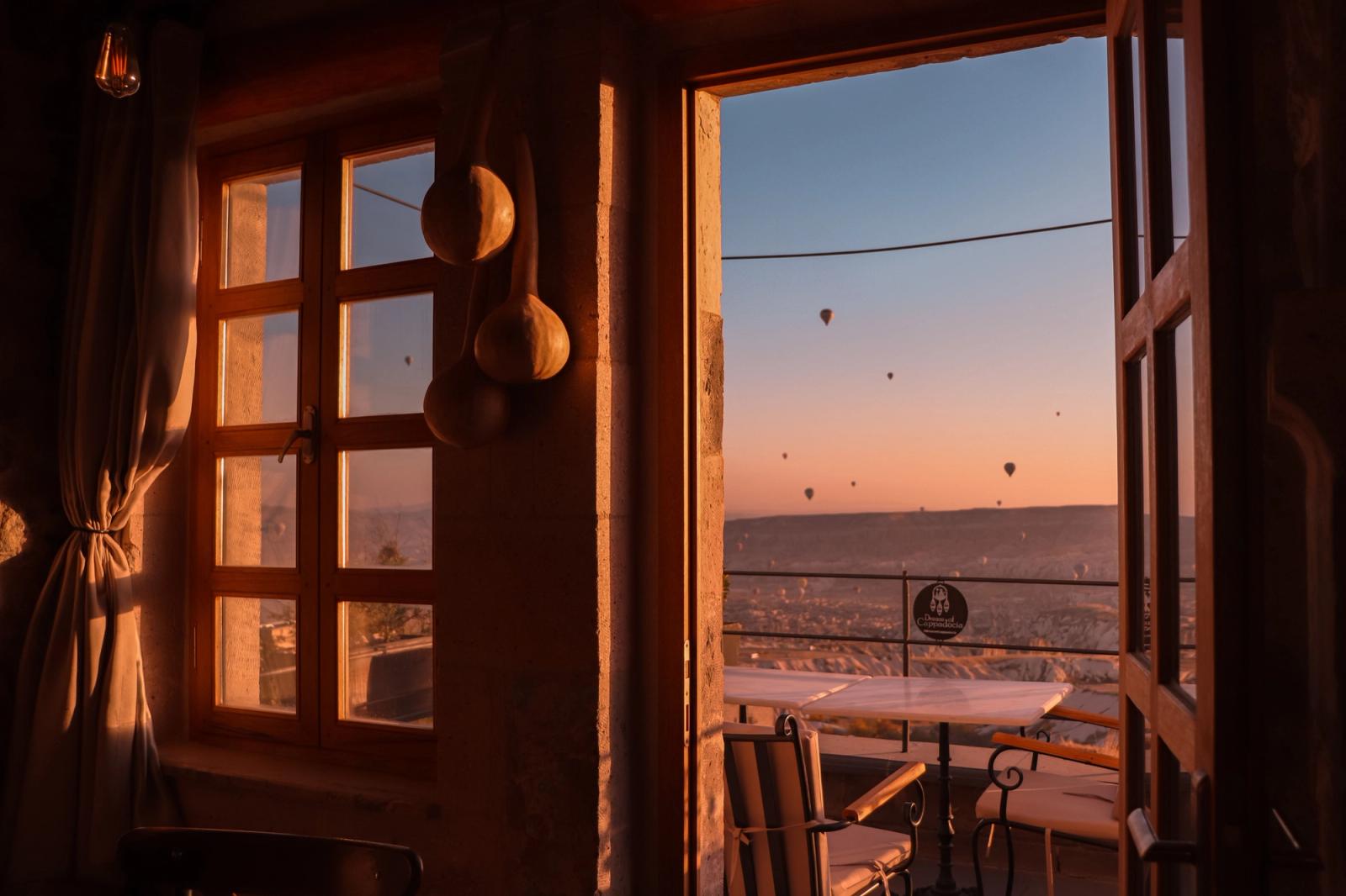 Captivating view of hot air balloons over a Turkish landscape at sunset from a cozy terrace